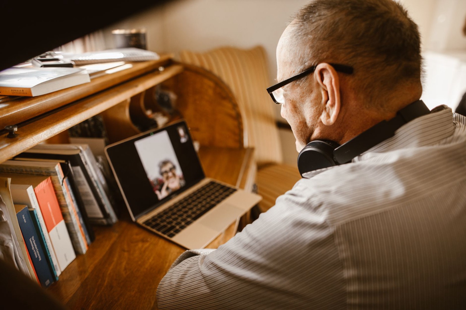 A person practising spoken English on a video call with headphones and a laptop